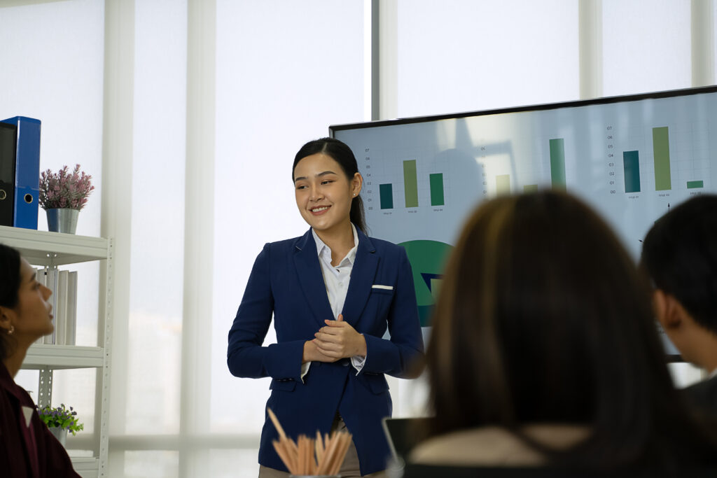 A young business professional giving a presentation in front of her colleagues in a boardroom.